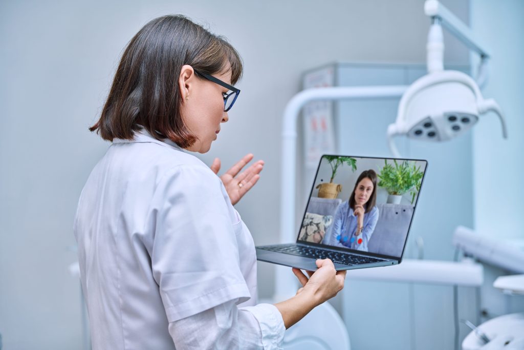 Doctor holds a laptop while conducting a telehealth session